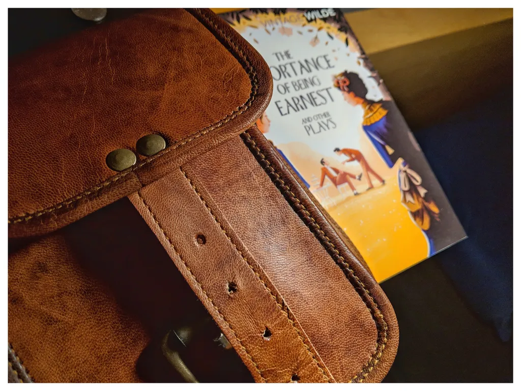 Geantă de piele și coperta cărții The importance of being Earnest de Oscar Wilde
